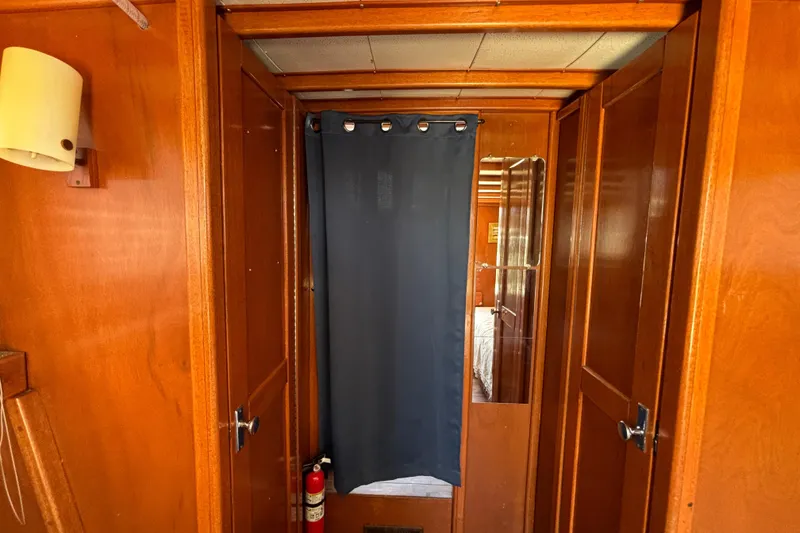 Interior of a 1974 Skookum 34 boat with wooden paneling and a blue curtain.