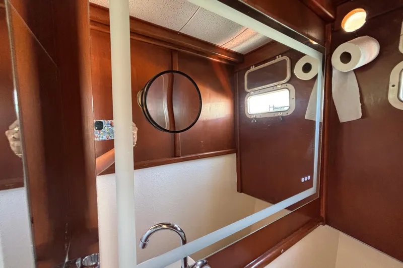 Bathroom interior of a 1974 Skookum 34 boat with mirror and porthole.