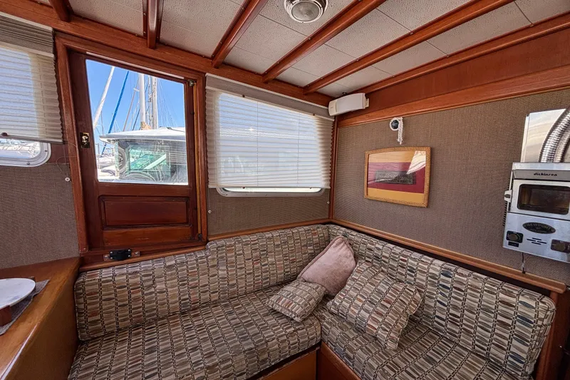 Cozy interior of a 1974 Skookum 34 boat with patterned seating and wooden accents.