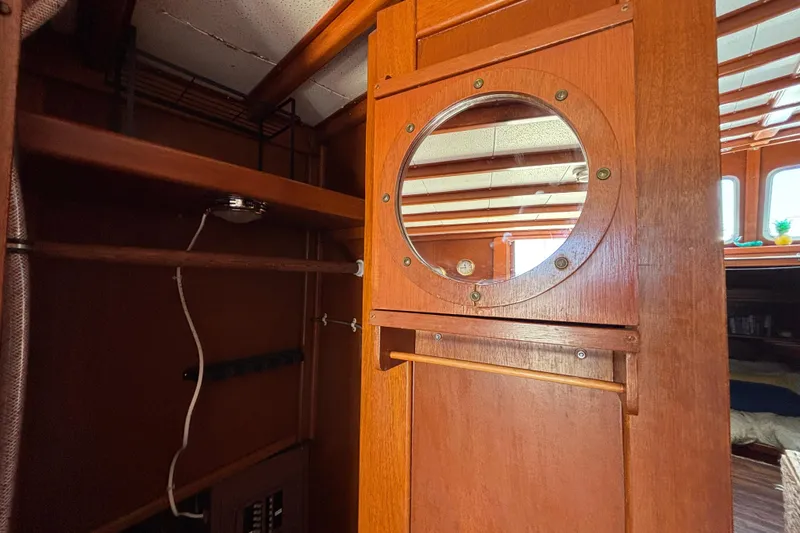 Interior of a 1974 Skookum 34 boat featuring wooden cabinetry and a round porthole.