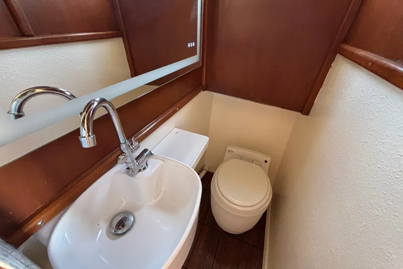 Compact bathroom in a 1974 Skookum 34 boat, featuring a sink and toilet.