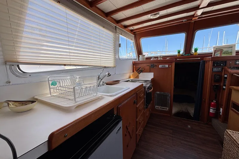 Interior of a 1974 Skookum 34 boat featuring a compact kitchen with wooden cabinetry.