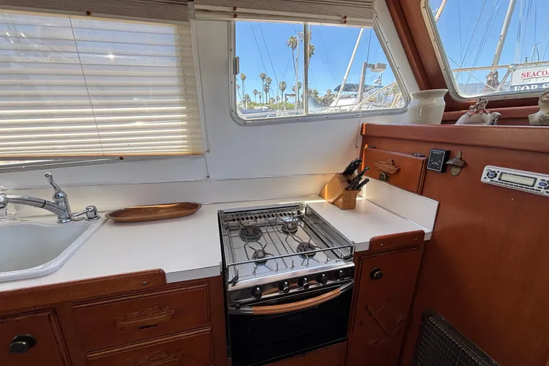 1974 Skookum 34 yacht kitchen with stove, sink, and wooden cabinetry.