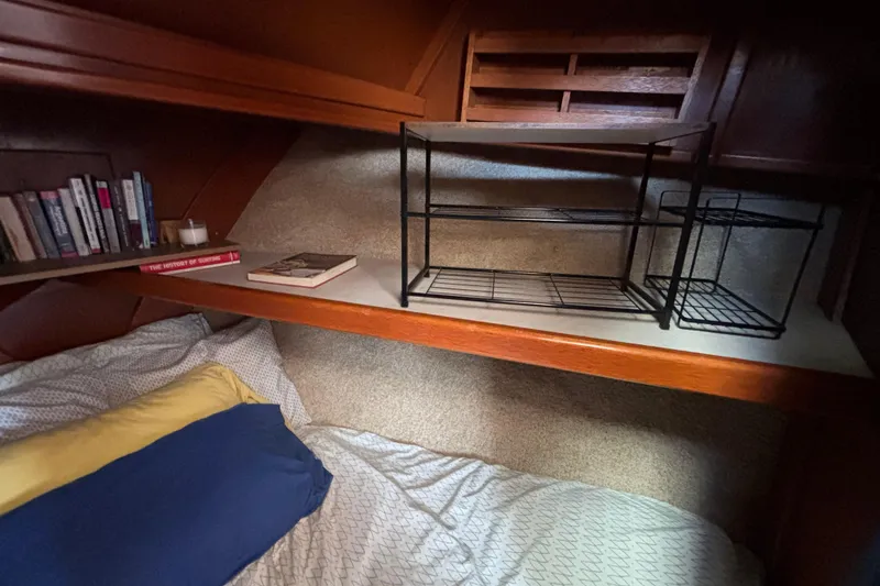 Cozy cabin interior of a 1974 Skookum 34 sailboat with books and bedding.
