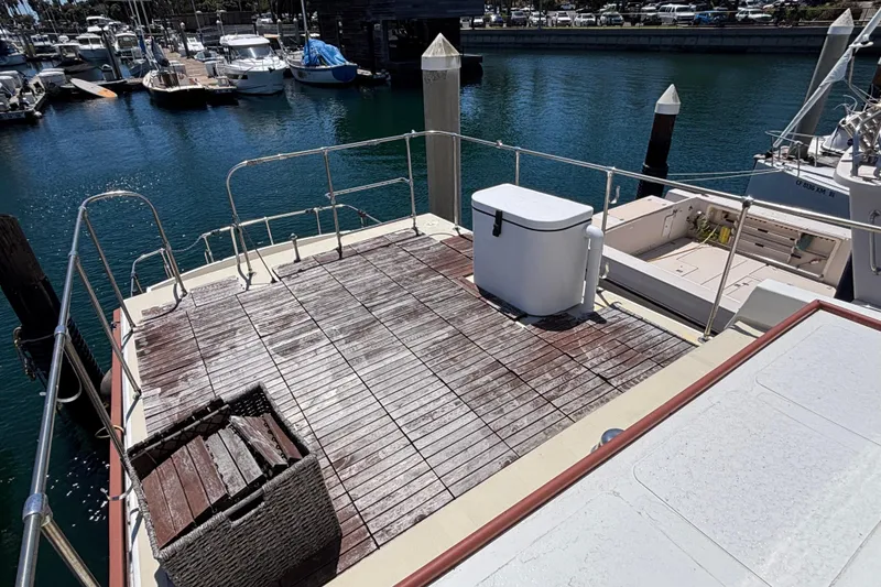 Deck of 1974 Skookum 34 boat at marina, featuring wooden flooring and storage box.