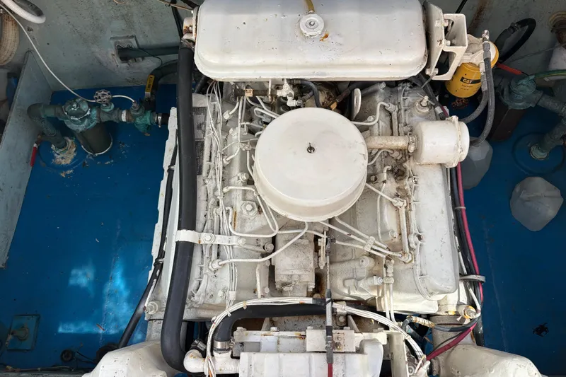 Engine compartment of a 1974 Skookum 34 boat, showcasing mechanical components and hoses.