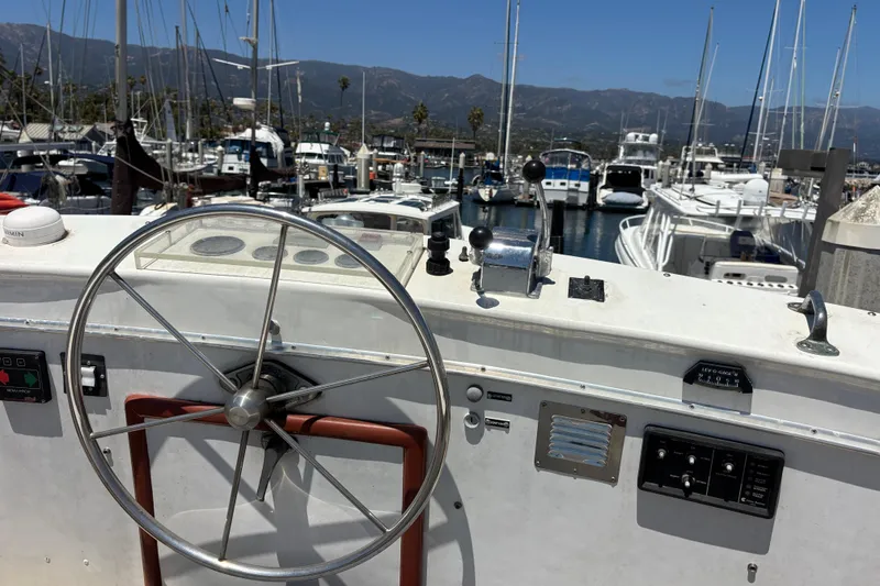 Steering wheel of a 1974 Skookum 34 boat docked in a marina.
