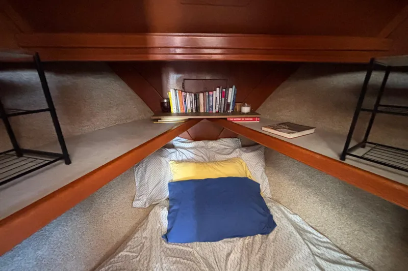 Cozy cabin interior of 1974 Skookum 34 sailboat with books and bedding.