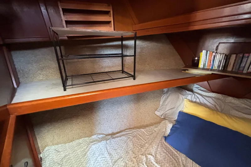 Cozy cabin interior of 1974 Skookum 34 sailboat with bed, shelf, and books.
