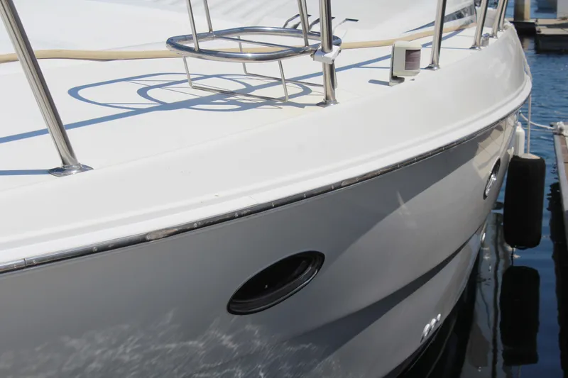 1996 Trojan 440 Express yacht docked, showcasing sleek white hull and stainless steel railings.