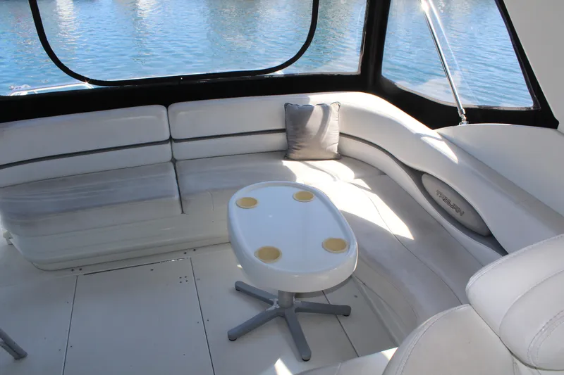 1996 Trojan 440 Express yacht interior with white seating and table, overlooking water.