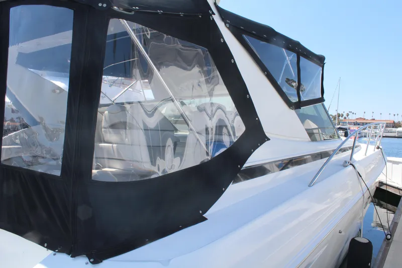1996 Trojan 440 Express yacht with black canvas enclosure at a marina.