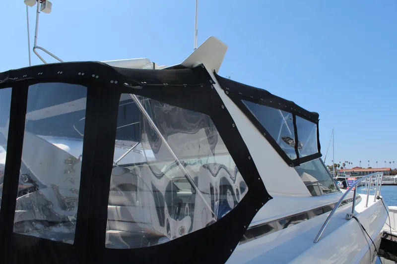 1996 Trojan 440 Express yacht with black canvas enclosure, docked under clear blue sky.
