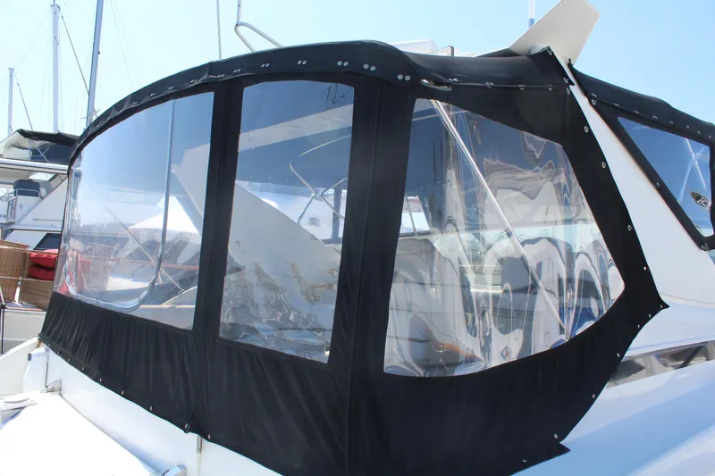 1996 Trojan 440 Express boat with black canvas enclosure in marina.