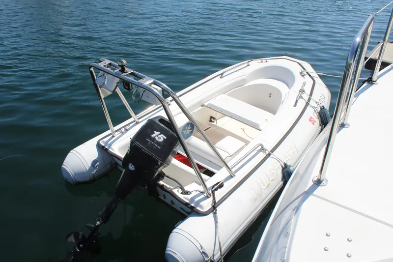 Inflatable boat with outboard motor docked on water, near Trojan 440 Express, 1996 model.