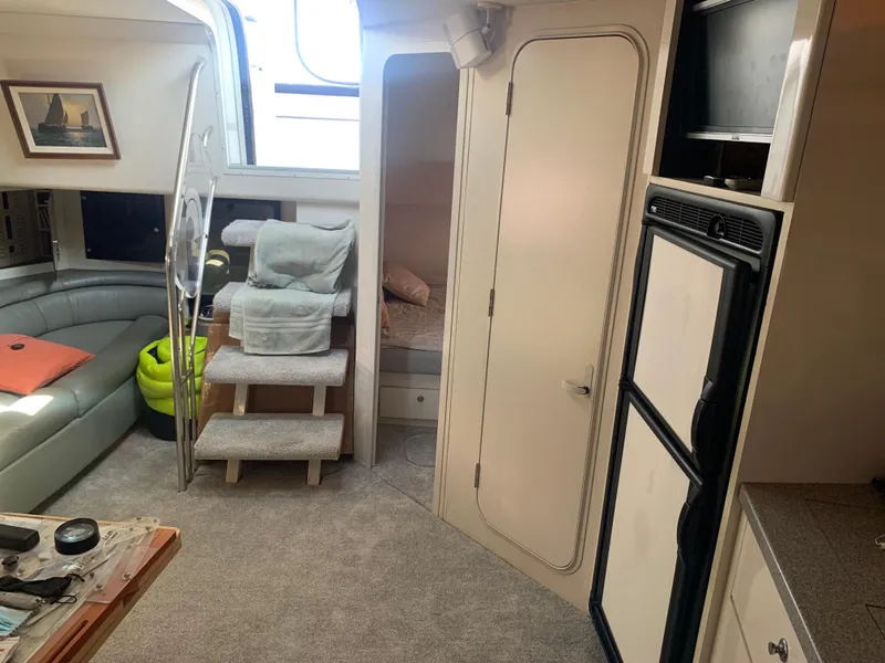 Interior of 1996 Trojan 440 Express yacht with cozy seating and compact kitchen area.