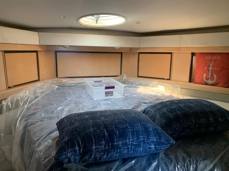 Cabin interior of 1996 Trojan 440 Express yacht with bed, pillows, and storage compartments.