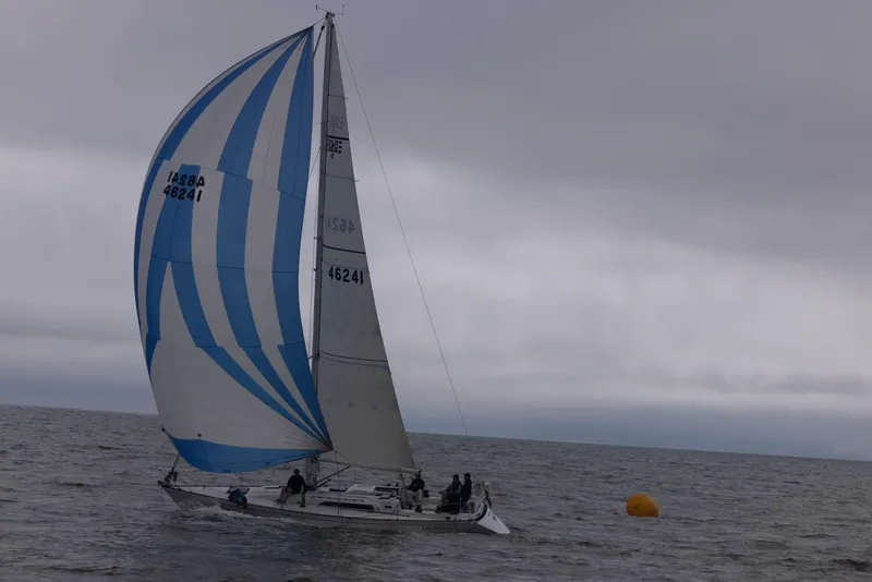 1985 C&C 41 sailboat with blue and white sail on the sea.