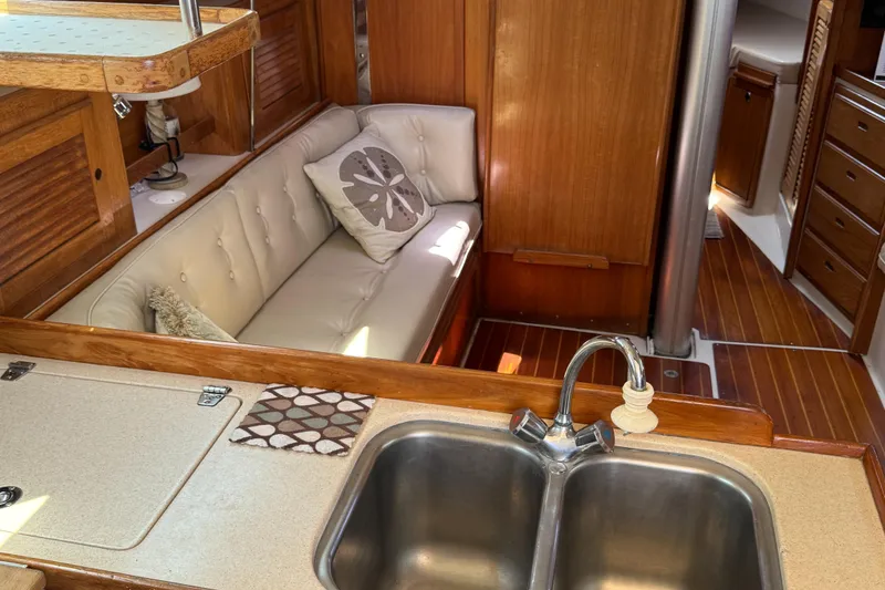Interior of a 1998 Catalina 36 MkII sailboat with a cozy seating area and kitchen sink.