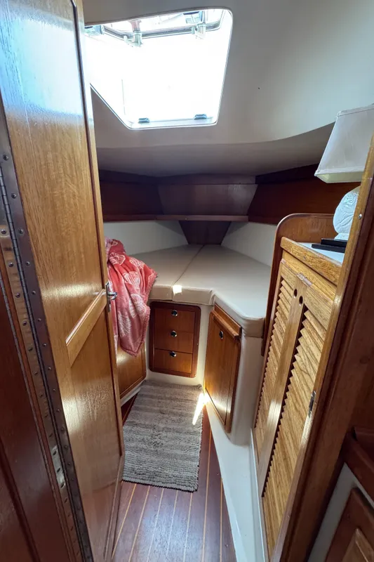Interior cabin of 1998 Catalina 36 MkII sailboat with wooden finishes and cozy bedding.