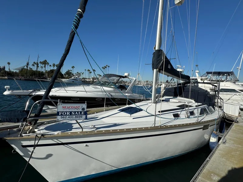 1992 Hunter 35 sailboat docked, for sale sign visible, clear blue sky background.