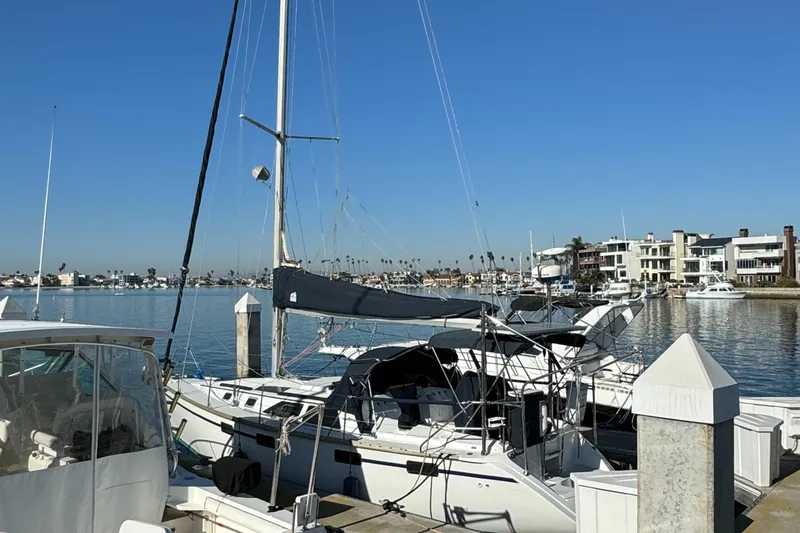 Sailboat docked at marina, Hunter 35 model, clear blue sky, waterfront homes in background.
