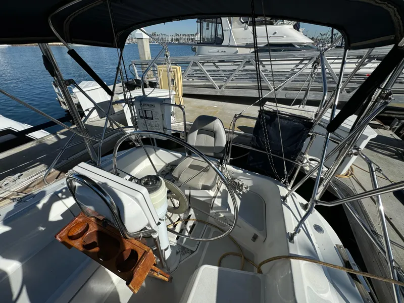 Cockpit of 1992 Hunter 35 sailboat docked at marina, featuring steering wheel and seating.