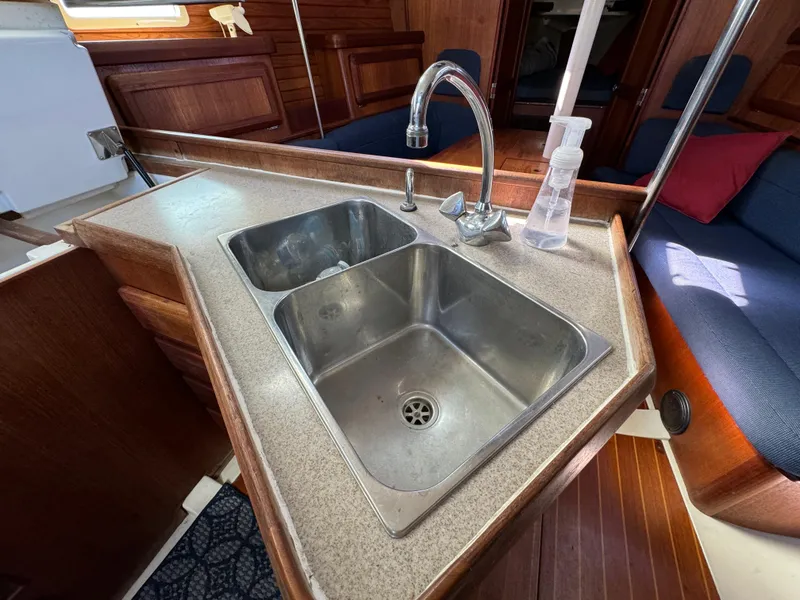 1992 Hunter 35 yacht kitchen sink with faucet, wooden interior, and seating area.