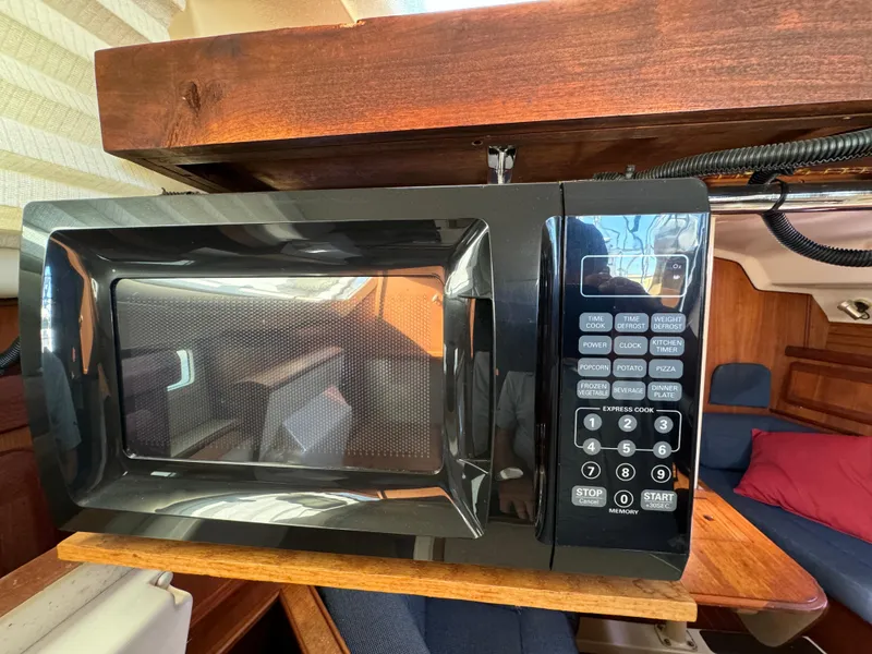 Microwave in a 1992 Hunter 35 yacht interior, wooden cabinetry, and seating area.