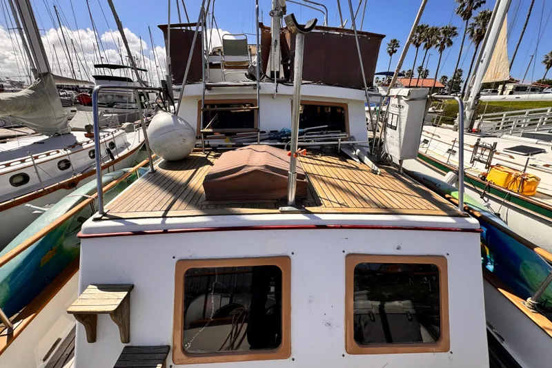 1980 Hershine Trawler docked, showcasing wooden deck and nautical equipment under clear skies.