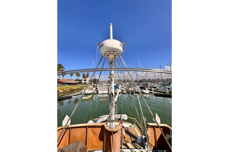 1980 Hershine Trawler docked in marina, clear blue sky, palm trees in background.