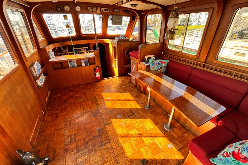 1980 Hershine Trawler interior with wooden flooring, red seating, and nautical decor.