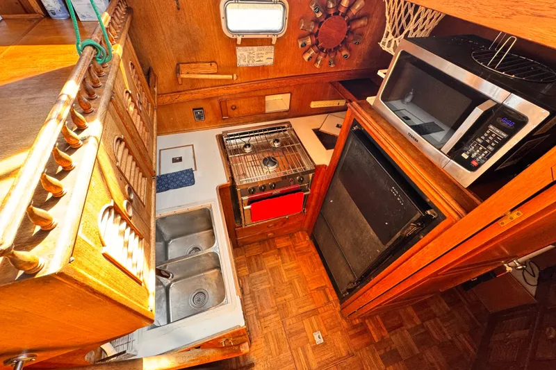 1980 Hershine Trawler kitchen with stove, microwave, and double sink in wooden interior.