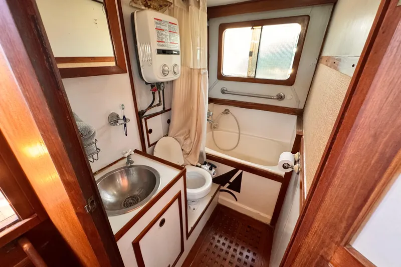1980 Hershine Trawler bathroom with sink, toilet, and shower in compact wooden interior.