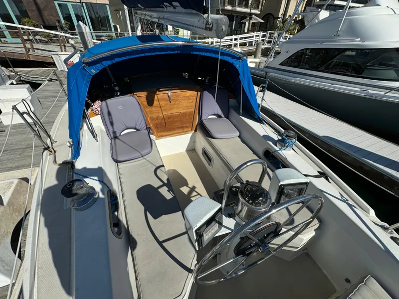 1987 Catalina 34 sailboat cockpit with blue canopy and dual seating at marina.
