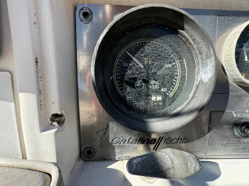 Close-up of a cracked RPM gauge on a 1987 Catalina 34 yacht dashboard.