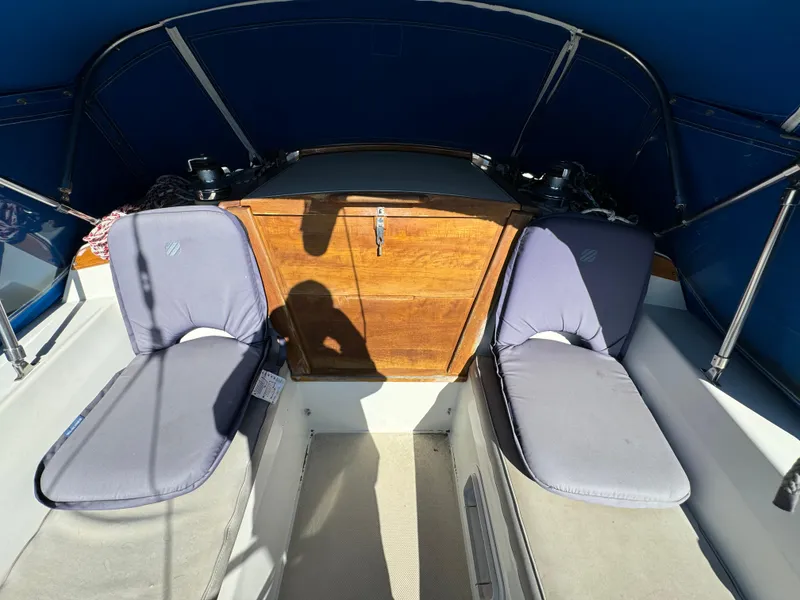 1987 Catalina 34 sailboat cockpit with cushioned seating and wooden hatch under blue canopy.