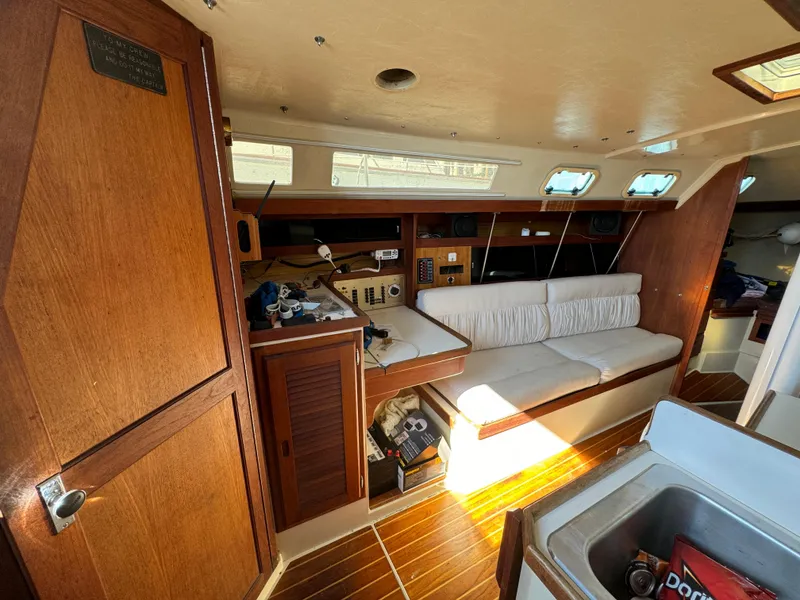 Interior of 1987 Catalina 34 sailboat with wooden cabinetry and cushioned seating.