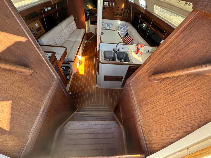 Interior of 1987 Catalina 34 sailboat with wooden finish and cozy seating area.