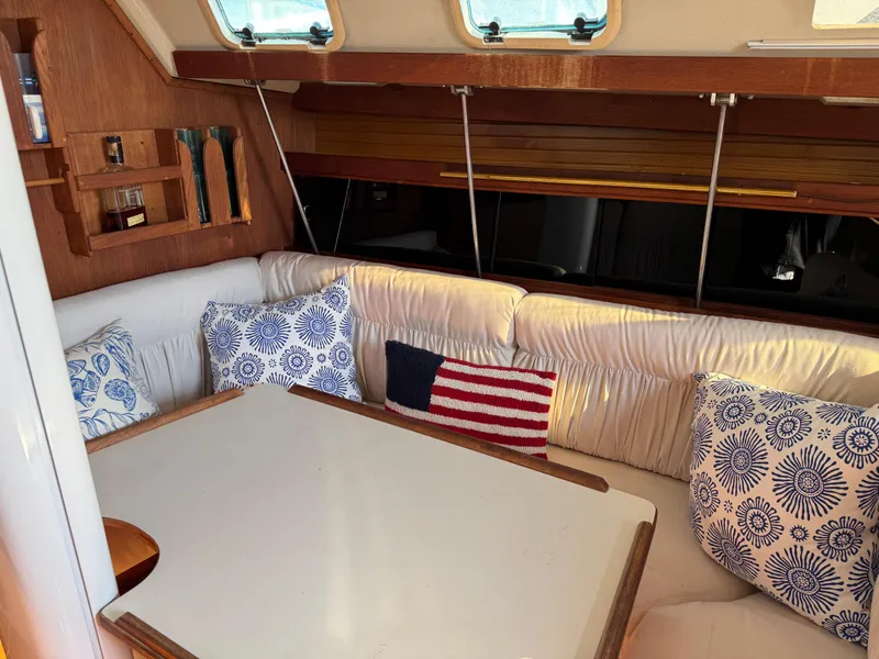 Cozy interior of 1987 Catalina 34 sailboat with cushions and American flag decor.