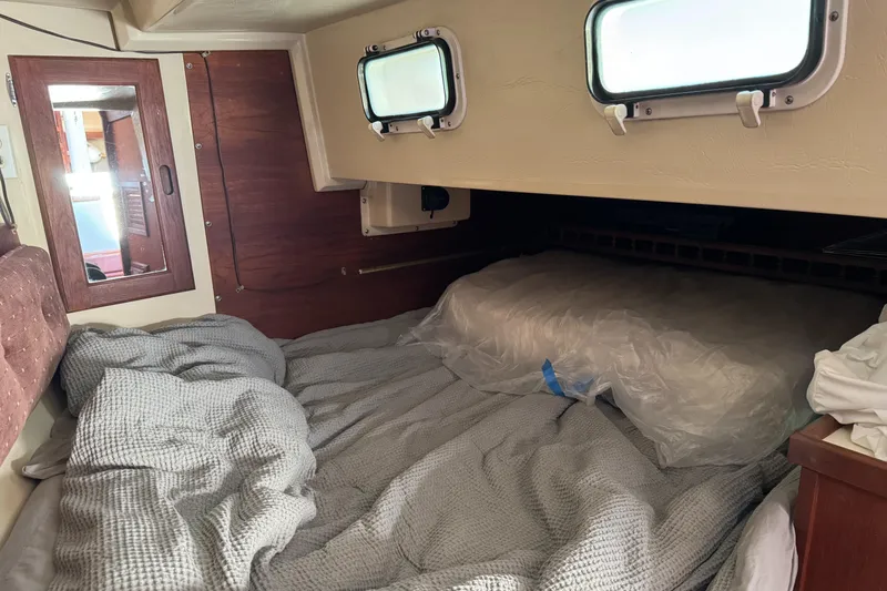 Cozy cabin interior of a 1987 Catalina 34 sailboat with bedding and portholes.