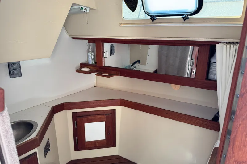 Interior of 1987 Catalina 34 sailboat with wooden cabinetry and compact sink area.