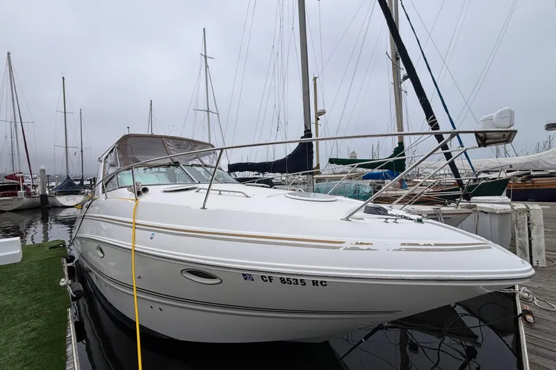2004 Larson 310 boat docked at marina, surrounded by sailboats on a cloudy day.
