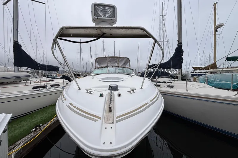 2004 Larson 310 boat docked at marina, surrounded by sailboats on a cloudy day.