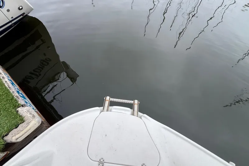 Bow of a 2004 Larson 310 boat docked on calm water.