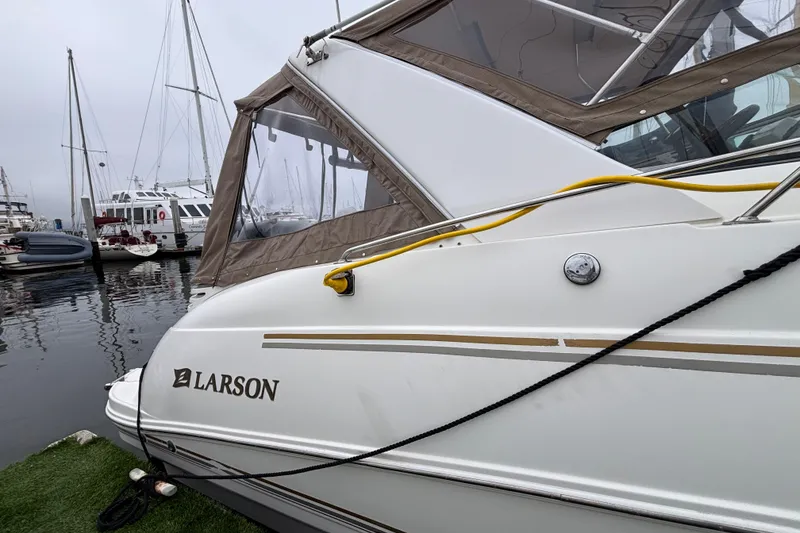 2004 Larson 310 boat docked at marina with other vessels in background.