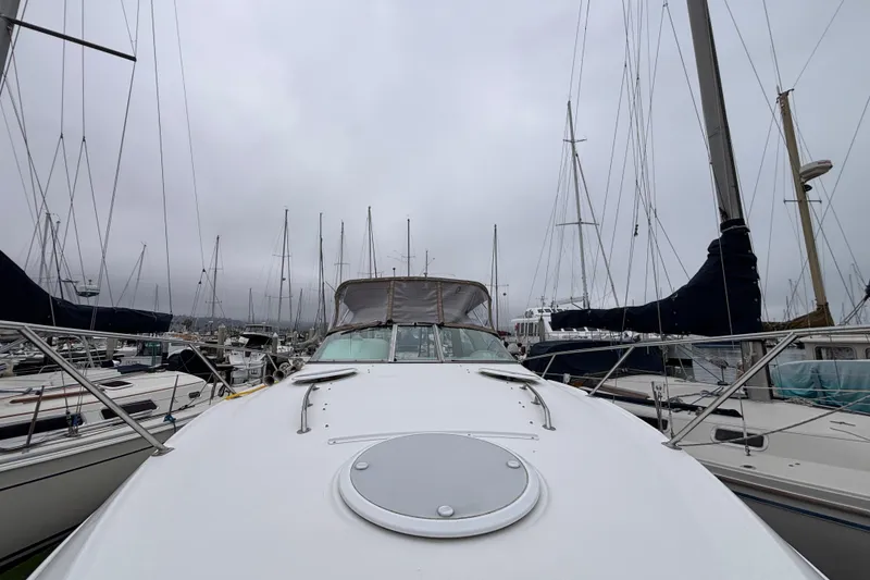 2004 Larson 310 boat docked in a marina, surrounded by sailboats under cloudy skies.