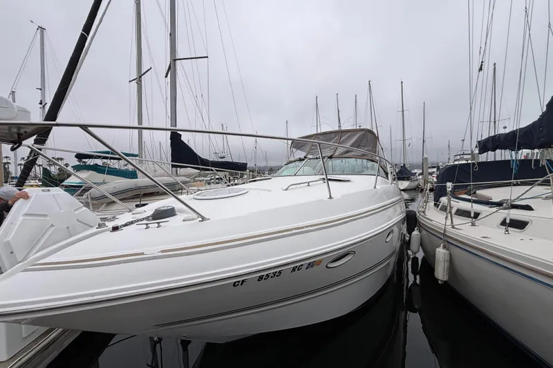 2004 Larson 310 boat docked among sailboats in a marina on a cloudy day.