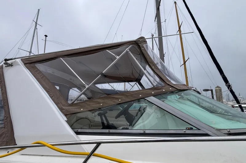 2004 Larson 310 boat with canopy, docked at marina under cloudy sky.