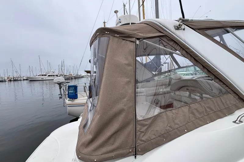 2004 Larson 310 boat docked in a marina with beige canopy.